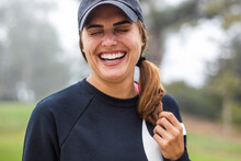 Close-up Of Cheerful Woman With Eyes Closed Wearing Cap And Sports Clothing At Park