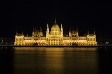 Illuminated Hungarian Parliament Building By Danube River Against Sky At Night