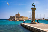 Fototapeta  - Mandraki port with deers statue, where The Colossus was standing and fort of St. Nicholas. Rhodes, Greece. Hirschkuh statue in the place of the Colossus of Rhodes, Rhodes, Greece
