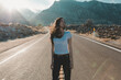 © Cavan Images - Young woman with eyes closed standing on road against mountains during sunny day