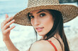 © Cavan Images - Close-up portrait of woman wearing hat while standing at beach
