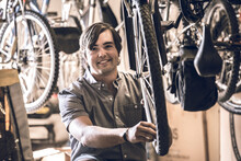Portrait Of Owner Repairing Bicycle Tire In Workshop