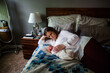 © Cavan Images - High angle view of mother lying by sleeping newborn son on bed at home
