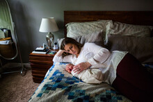 High Angle View Of Mother Lying By Sleeping Newborn Son On Bed At Home