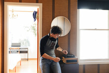 Man Playing Record Player While Sanding By Entrance At Home