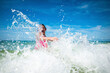 © Cavan Images - Playful girl splashing water in sea against sky during sunny day