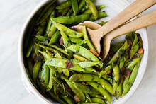 Overhead View Of Fried Pea Pods With Wooden Spoons In Container On Table