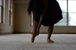 © Cavan Images - Low section of woman wearing ballet shoe while standing on wooden floor in old building
