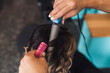 © Cavan Images - Cropped hands of hairdresser using curling tongs on customer's hair in salon