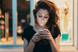 © Cavan Images - Woman using smart phone while sitting against store at night