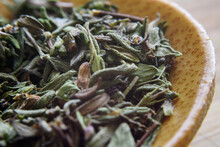 Close-up Of Dry Herbs In Wooden Spoon On Table