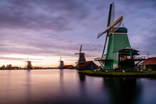 Traditional Windmills By Canal Against Cloudy Sky During Sunset