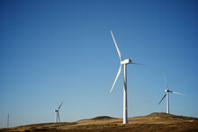 Windmills On Land Against Clear Blue Sky