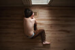 © Cavan Images - Young boy with no shirt looking into heating vent on the floor