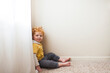 © Cavan Images - Young boy in yellow shirt sits in corner of bedroom at home by window