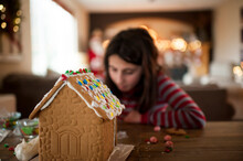 Gingerbread House Being Decorated By Little Girl During The Holidays