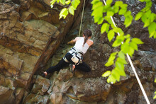 Young Woman Rock Climbing Outdoors In Summer