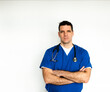 © Cavan Images - Medical doctor in scrubs with arms folded against white backdrop.