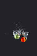 Cherry Tomato And Brussel Sprout Splash Water Over A Dark Background