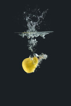 Yellow Pear Thrown Into The Water On Black Background