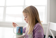 Side View Of Girl Eating Out Of A Coffee Mug