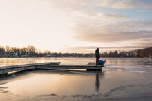 Two Boys At Sunset On Dock By Frozen Water