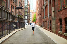 A Female Runner Running In The Urban Streets Of Boston.