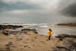 © Cavan Images - Child looks at raging sea at beach during storm on windy day