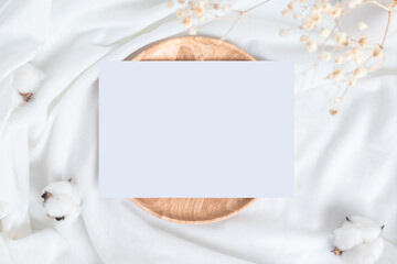 A table with cotton flowers and wood plate or tray and blank card.