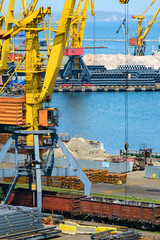 Wall Mural - industrial seaport infrastructure - sea, cranes and metal workpieces, bundles of wire, railcars on railroad, concept of marine cargo transportation