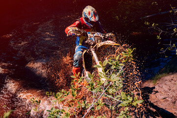 Wall Mural - motorcycle racer on an enduro sports motorcycle crosses a river in a ford in an off-road race in summer on a sunny day