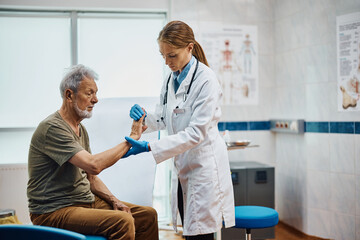 Female doctor examining hand of senior patient at medical clinic.