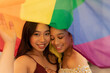 © PintoArt - two multiracial lesbian women, of Hispanic and Asian origin, wrapped in a gay pride rainbow flag
