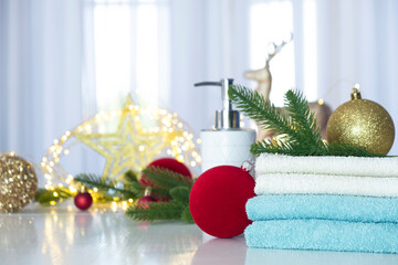 Stack of blue and white towels folded on the table, fir branches, Christmas balls and Christmas lights. SPA massage or beauty salon, relaxation and wellness in Christmas or New Year variant.