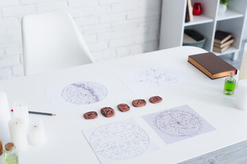 Wall Mural - astrological maps and clay runes near candles and prediction book on white table.