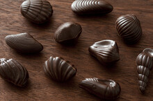 Tasty Sweet Belgian Chocolates Formed As Seashells Spread Out On Dark Wooden Table