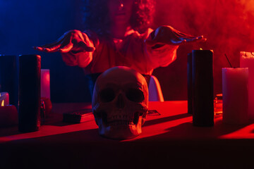 Wall Mural - cropped view of blurred medium near skull and candles on dark background with colorful smoke.