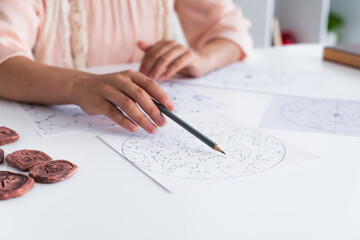 Wall Mural - cropped view of blurred astrologist pointing at celestials map with pencil.