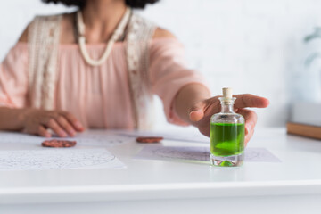 Wall Mural - selective focus of bottle with essential oil near cropped astrologer and clay runes.