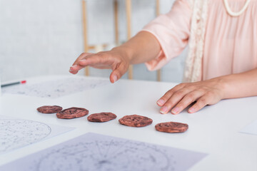 Wall Mural - cropped view of fortune teller near clay runes and cosmic maps during spiritual session.