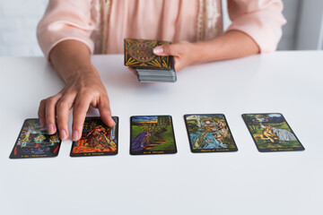 Wall Mural - KYIV, UKRAINE - JUNE 29, 2022: cropped view of fortune teller near tarot cards on table.