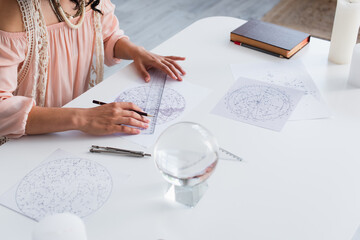 Wall Mural - partial view of young astrologer drawing cosmic charts near magic crystal.