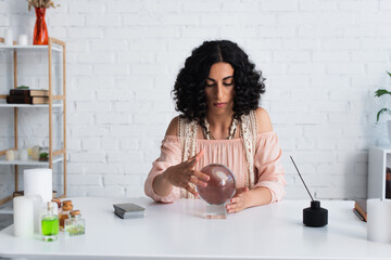 Wall Mural - brunette astrologist touching magic sphere near tarot cards and diffuser with aroma stick.