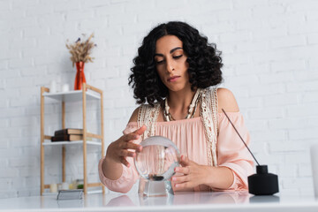 Wall Mural - brunette soothsayer holding hands near crystal ball and diffuser with aroma stick.