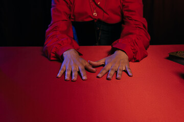 Wall Mural - cropped view of medium with hands on red table isolated on black.