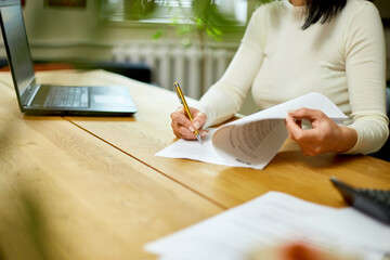 Woman hand signing a contract, making a deal with business partner. Female signs the documents at office.