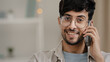 © Yuliia - Portrait indoor male customer client business man guy boyfriend with glasses arab talking mobile phone answering call chatting friendly happy carefree remote conversation orders delivery by calling