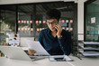 © Nuttapong punna - Business asian man Talking on the phone and using a laptop with sitting at office