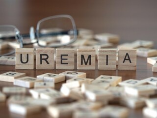 Sticker - uremia word or concept represented by wooden letter tiles on a wooden table with glasses and a book