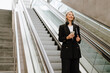 © Drobot Dean - Mature asian woman using mobile phone while standing on escalator